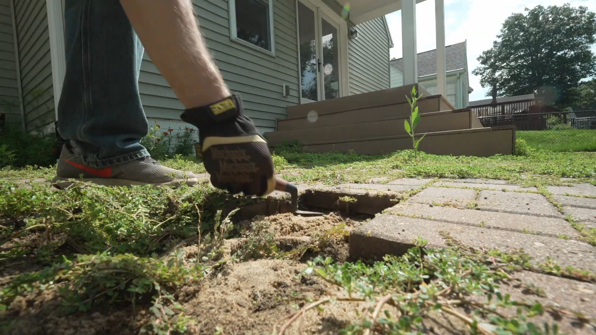 man pulling up brick paver with a margin trowel
